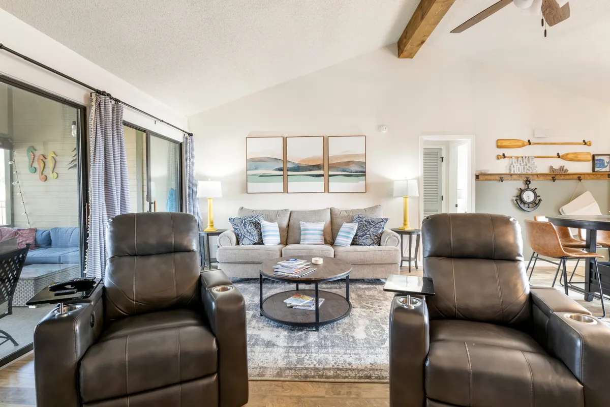 An inviting living area with a large sectional sofa, two recliners, a coffee table with magazines, and tasteful wall art. The room is designed for comfort and togetherness, encouraging both relaxation and social interaction.