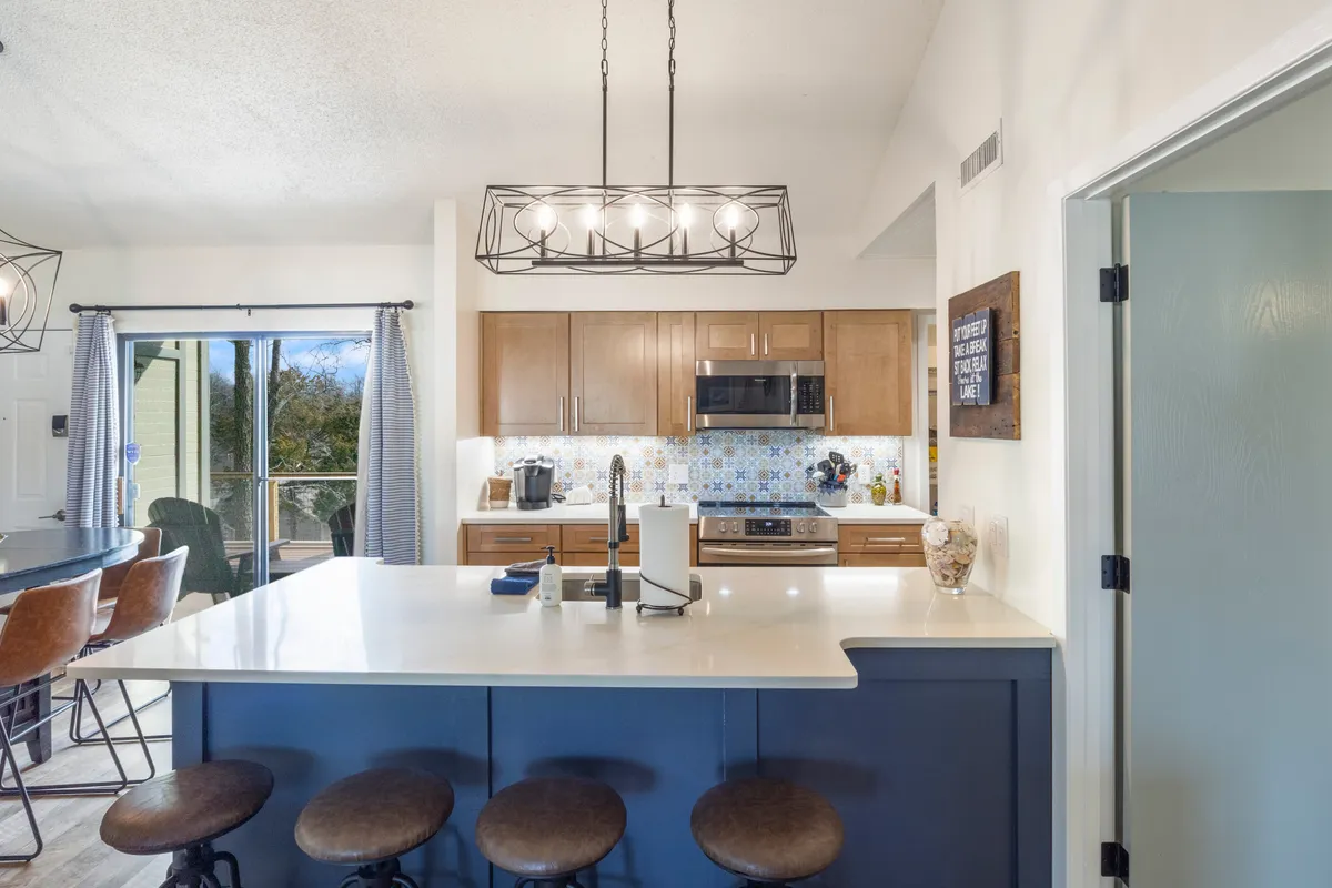 This interior shot centers on an island bar with stylish seating, a modern light fixture above, and a vibrant backsplash in the background. The setup encourages both intimate breakfasts and lively dinner parties, capturing the inviting spirit of communal dining.